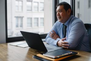 positive ethnic boss using laptop in light office